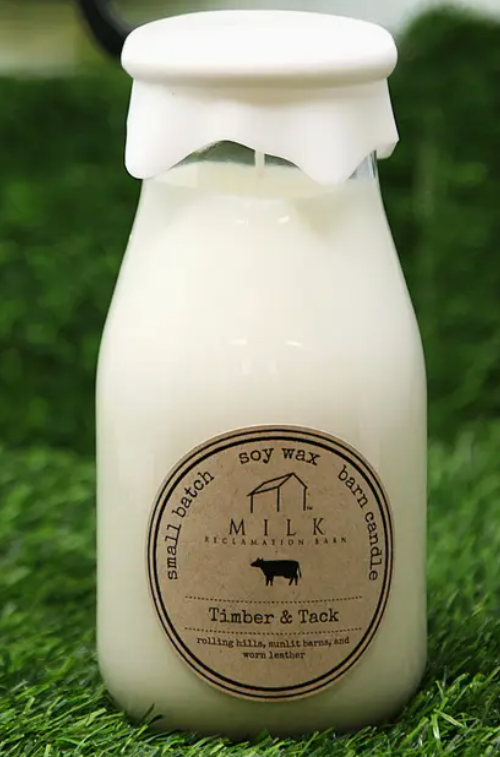 Soy wax candle in a bottle with a label on a grassy background