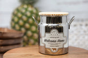 Silver milk churn with wooden lid on a wooden surface, blurred background