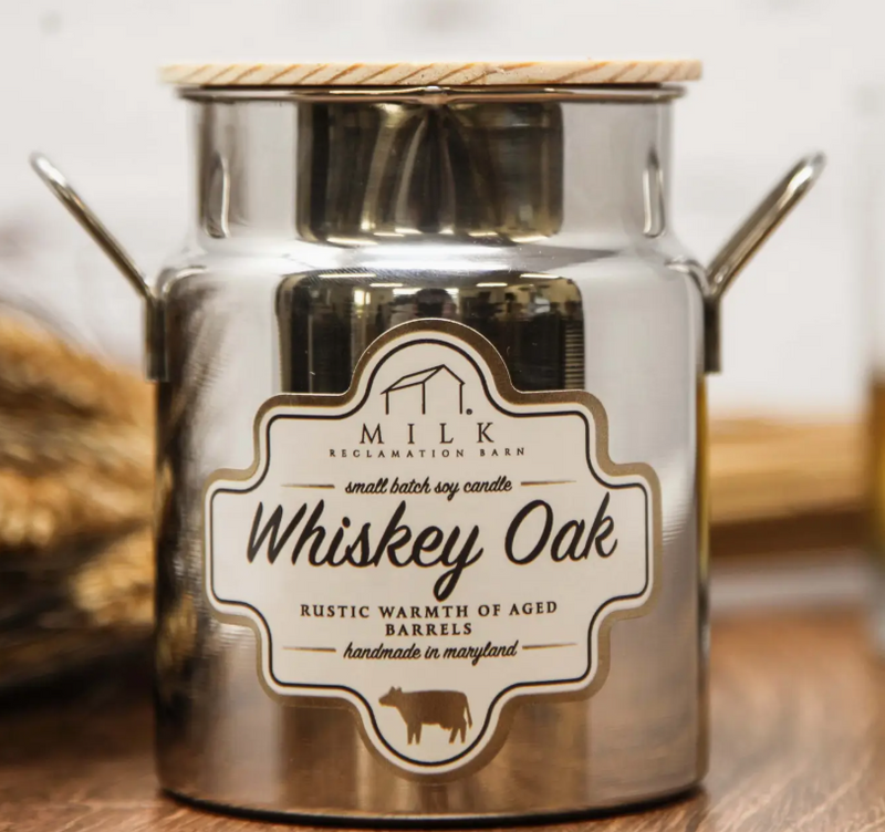 Silver candle jar with 'Milk Reclamation Barn' label on a wooden surface