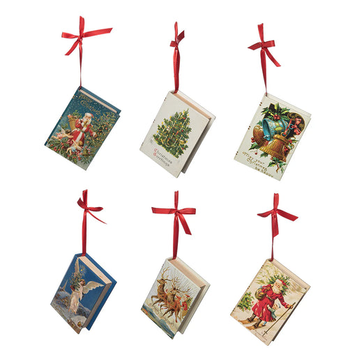 Set of six Christmas-themed book ornaments with red ribbons on a white background