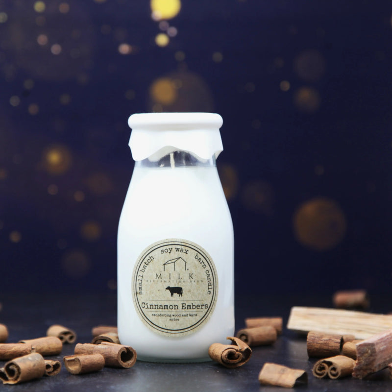 White milk bottle with a label surrounded by cinnamon sticks on a dark background