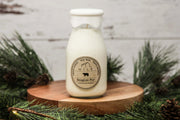 Milk bottle candle on a wooden stand with Christmas decorations