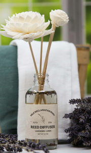 Reed diffuser with flowers and lavender on a white surface