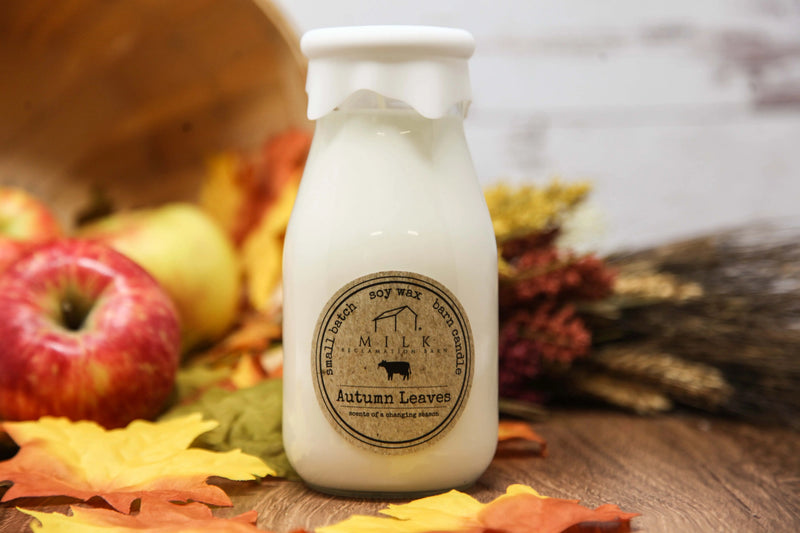 Bottle of milk with an autumn leaves label on a wooden surface with fall foliage.