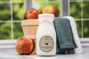 Bottle of milk with a label featuring apples and a basket in the background
