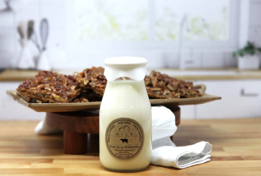 Bottle of milk with a label on a wooden table, with cookies in the background