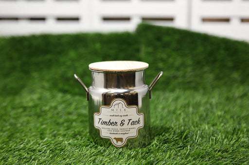 Metallic milk churn with 'Timber & Tack' label on grass