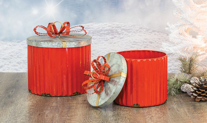 Two red gift boxes with ribbons on a wooden surface with a snowy landscape background.
