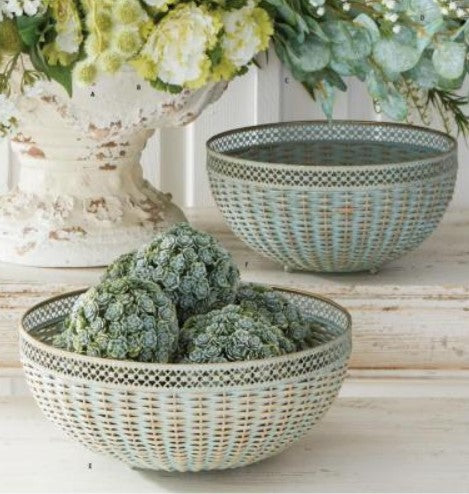 Decorative woven bowls with green decorative balls and flowers on a light wooden surface.