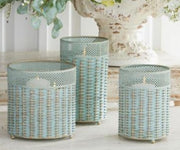 Three woven planters on a light wooden surface with a blurred floral background