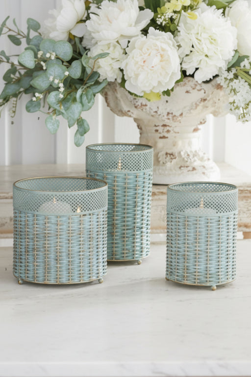Three woven planters on a light wooden surface with a blurred floral background