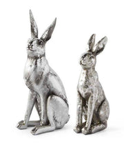 Two metallic silver rabbit figurines on a white background