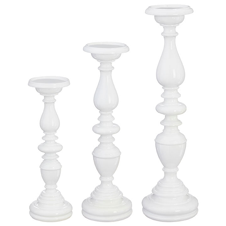 Three white candle holders of different heights on a white background