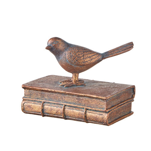 Bronze bird figurine on a book-shaped base against a white background