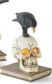 Skull with glowing eyes and a crow on its head, sitting on books.