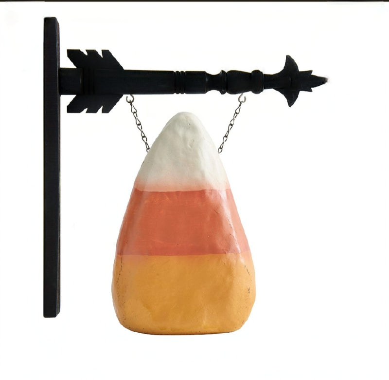 Decorative candy corn hanging from a black arrow-shaped hook on a white background