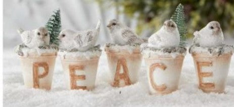 Decorative arrangement with birds in pots spelling 'PEACE' on a snowy background