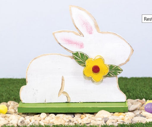 Decorative rabbit figure with a yellow flower on a grassy background