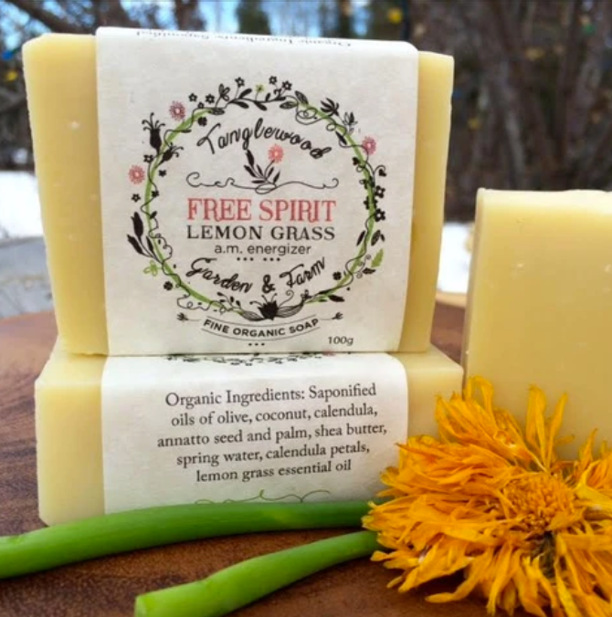 Two bars of soap with labels and a sunflower on a wooden surface
