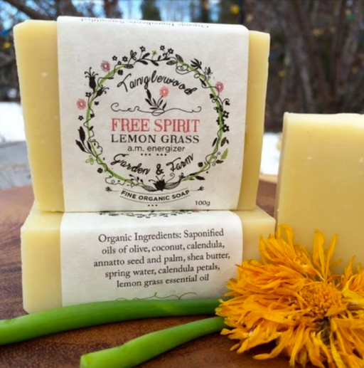 Two bars of soap with labels and a sunflower on a wooden surface