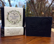 Tangletown Full Moon Magic soap bar and packaging on a wooden surface with a blurred natural background.