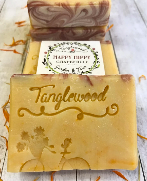 Two bars of soap with 'Tanglewood' branding on a light wooden surface.