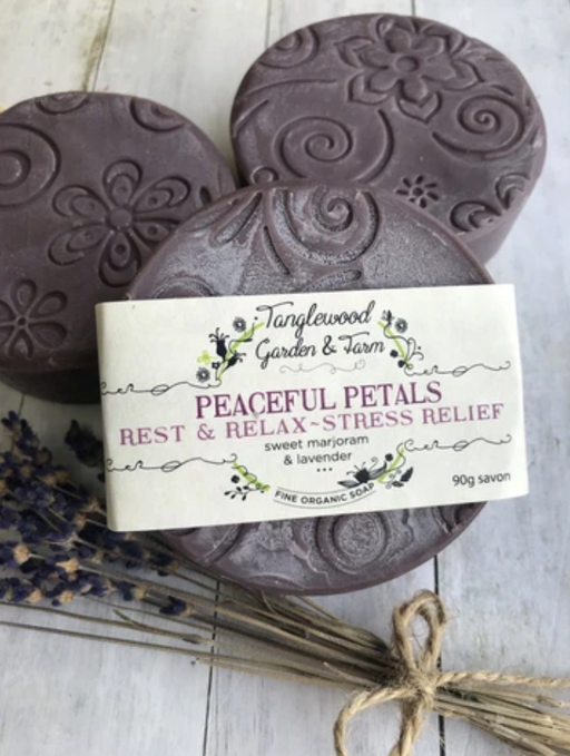 Three soap bars with a label on a wooden surface, featuring floral designs and lavender.
