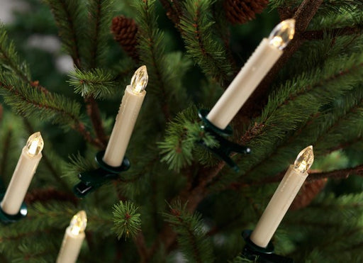 Decorative candles on a Christmas tree with green branches and pinecones.