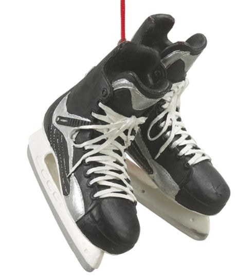 A pair of black hockey skates with white laces and blade guards, hanging by a red ribbon, against a white background.