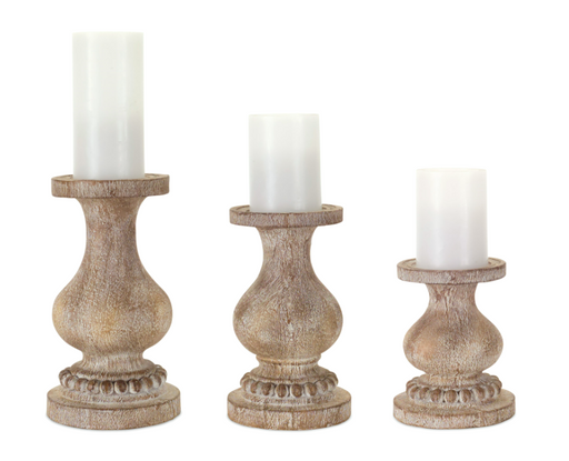 Three wooden candle holders with white candles on a white background