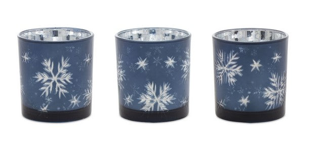 Three blue candle holders with white snowflake patterns on a white background