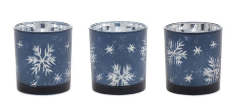 Three blue candle holders with white snowflake patterns on a white background