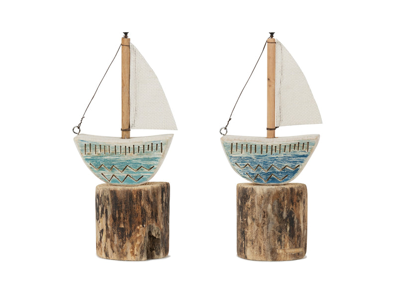 Two decorative sailboats on wooden stands with a white background