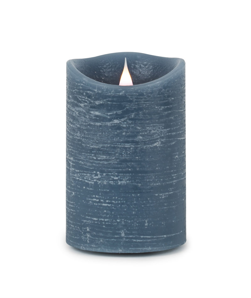 Blue textured candle with a lit wick on a white background
