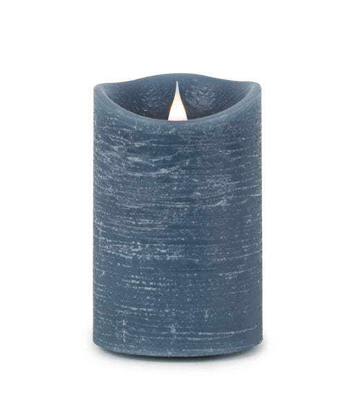 Blue textured candle with a lit wick on a white background