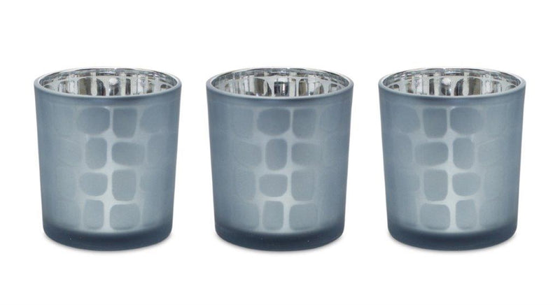 Three blue glass votive candle holders with silver bases on a white background