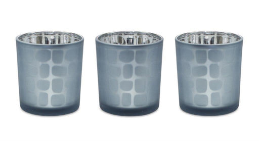 Three blue glass votive candle holders with silver bases on a white background