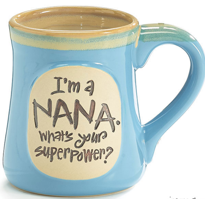 A light blue ceramic mug with a taupe rim and a hand-painted message that reads 'I'm a Nana. What's Your Superpower?'