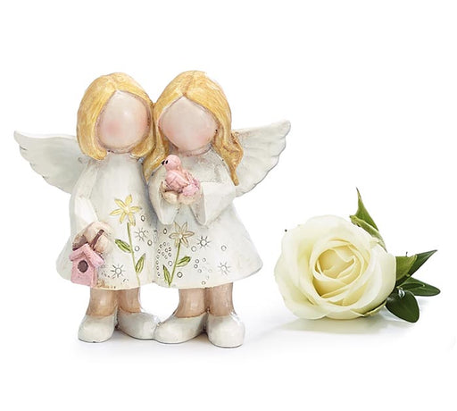 Two angel figurines with a white rose on a white background