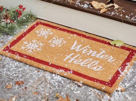 Doormat with 'Winter Hello' text and snowflake designs on a snowy surface.