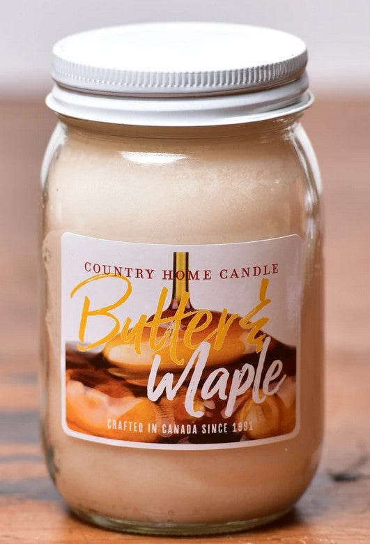 Jar of 'Butter & Maple' candle with a label on a wooden surface