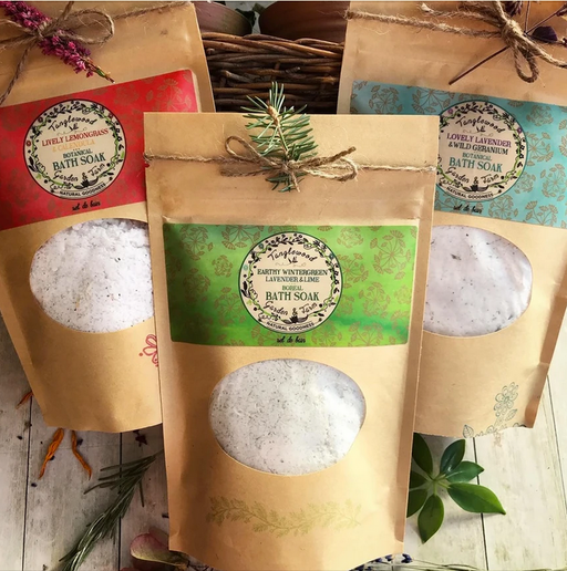 Bath soaks in brown paper bags with decorative labels on a wooden surface.