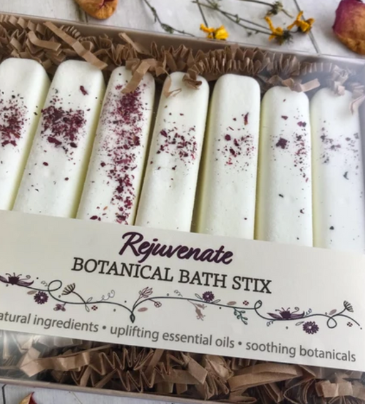 A package of white rectangular botanical bath stix with various botanicals sprinkled on top, displayed in a box.
