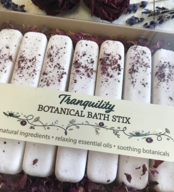 A package of white rectangular botanical bath stix with various botanicals sprinkled on top, displayed in a box.
