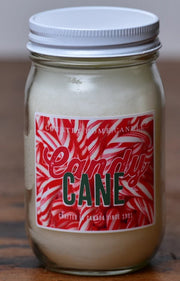 A jar of Candy Cane scented candle with a white lid and a label that has red and white stripes and text.