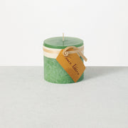 Green candle with a brown label on a white background