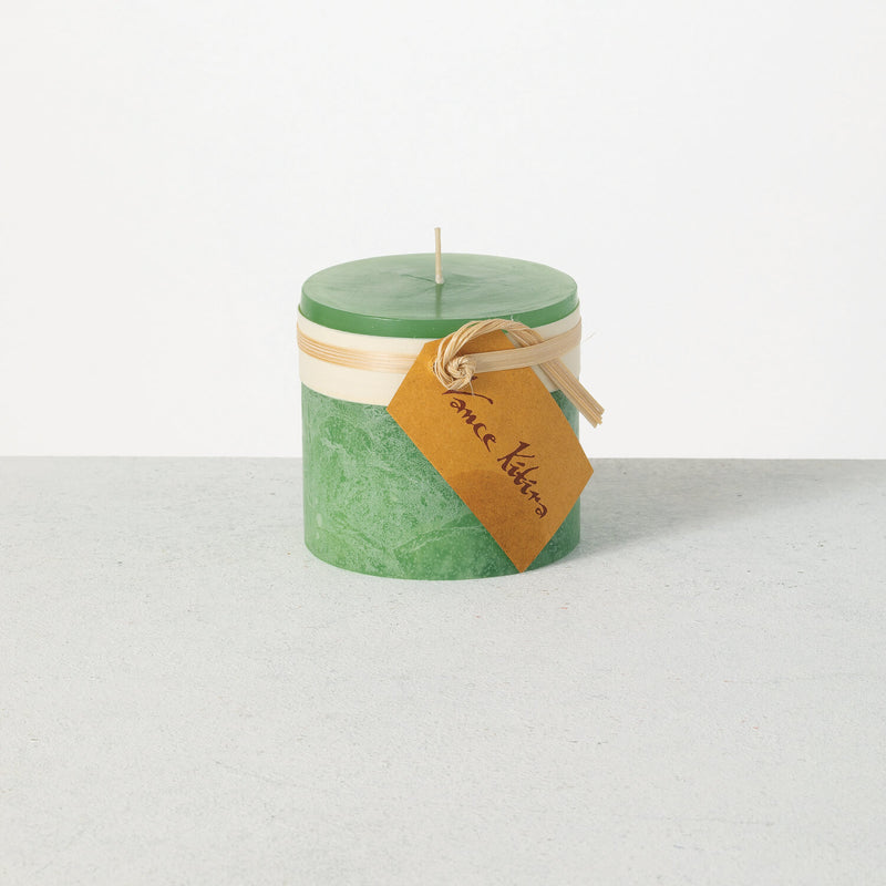 Green candle with a brown label on a white background