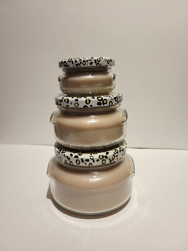 Stack of glass jars with animal print lids on a white background