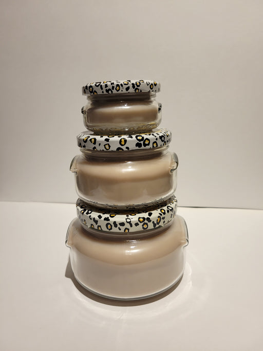 Stack of glass jars with animal print lids on a white background