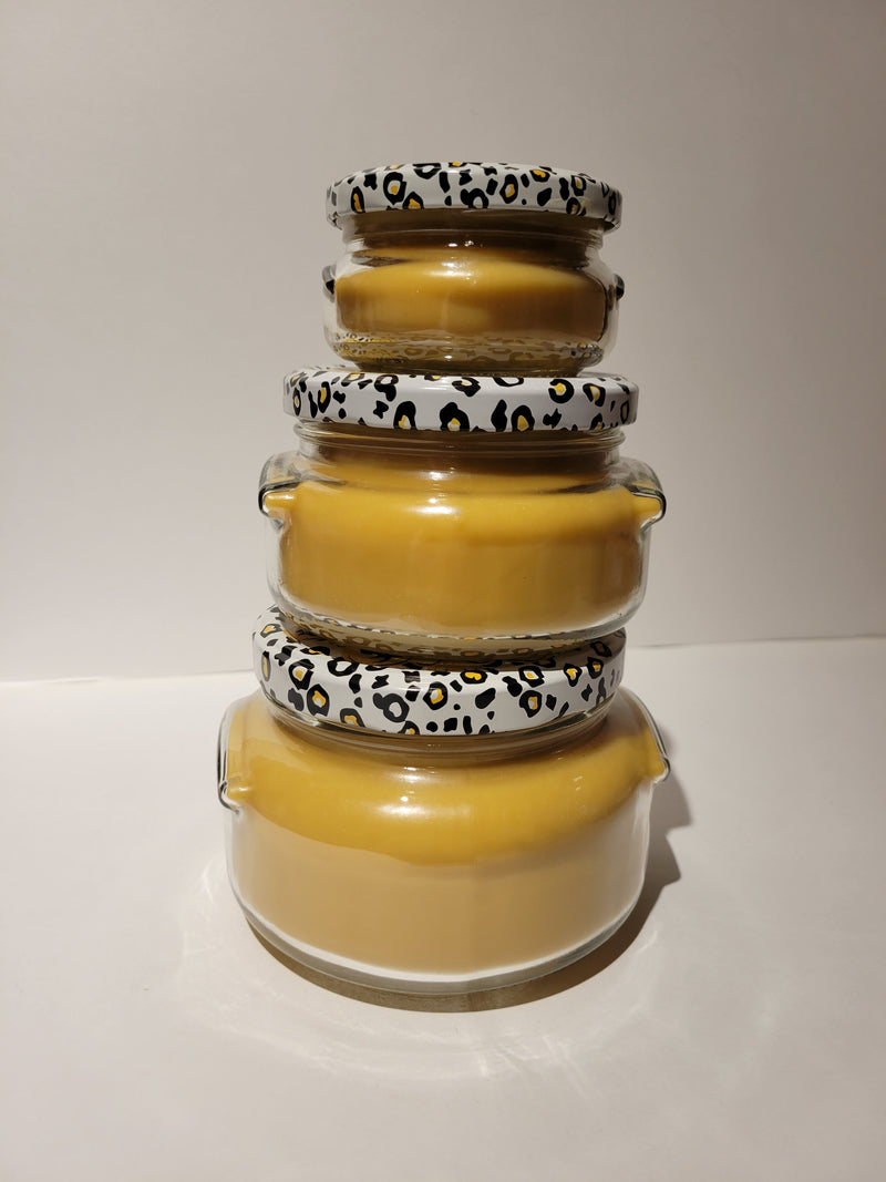 Stack of yellow glass jars with leopard print lids on a white background